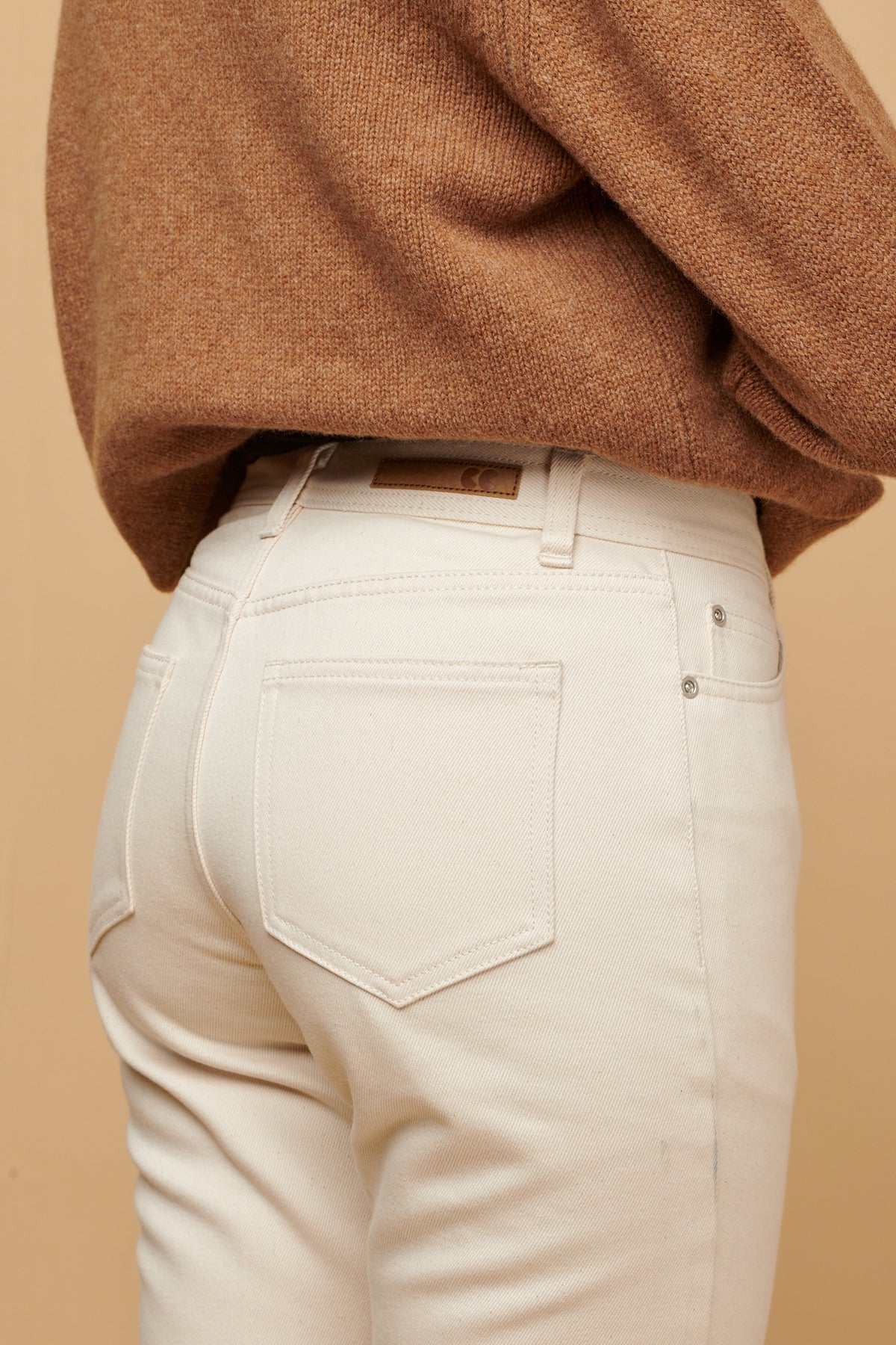 
            Close up of the back of Gloria jean in ecru, two back pockets, CC logo patch on the waistband with belt loops.