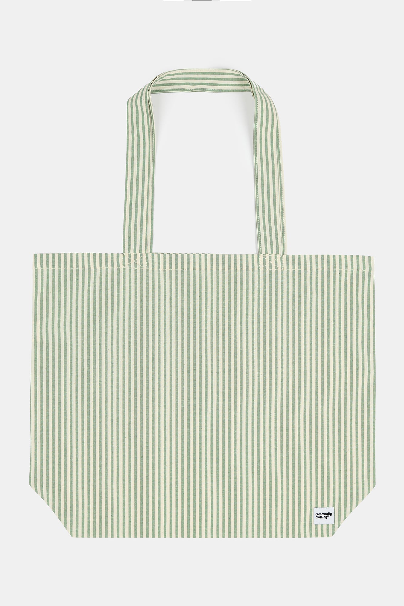 Stripe tote bag worn in the garden of quarry bank mill with flowers surrounding the green and white stripe tote bag
